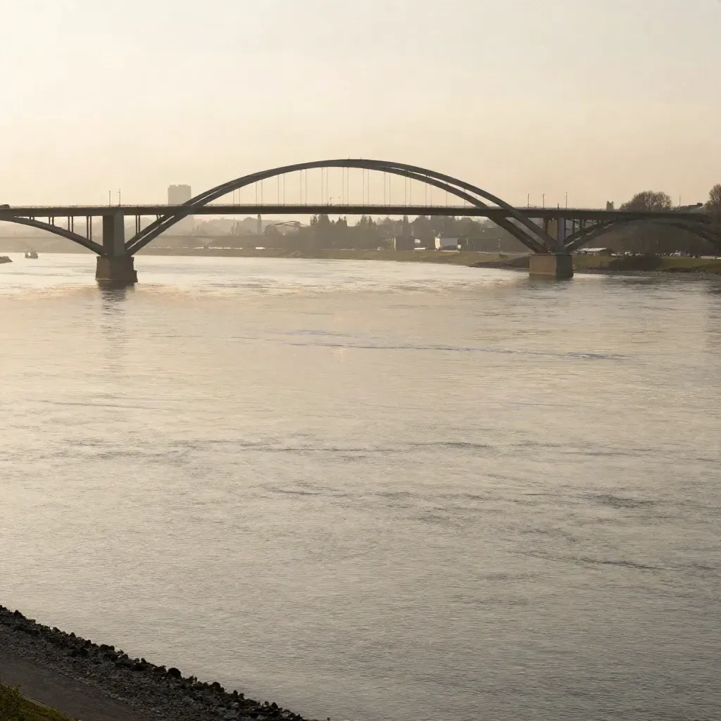 Rhein bei Leverkusen mit langer Brücke und nebliger Industrie im goldenen Abendlicht.